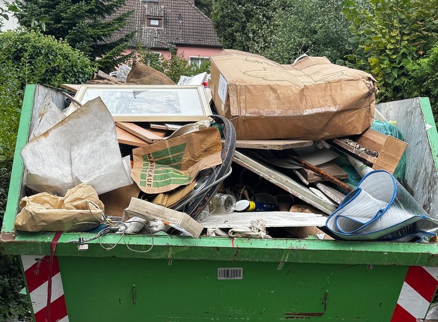 Container, gefüllt mit Hausrat aus einer Entrümpelung: Kartons, Bilderrahmen und Papiertüten