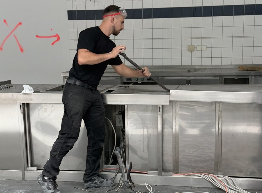 Mitarbeiter der Rückbauhelden hebelt eine Edelstahl-Küchenzeile mit dem Brecheisen aus